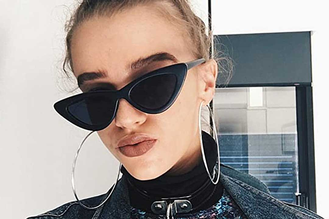 Young female wearing black triangular sunglasses frame and black leather jacket
