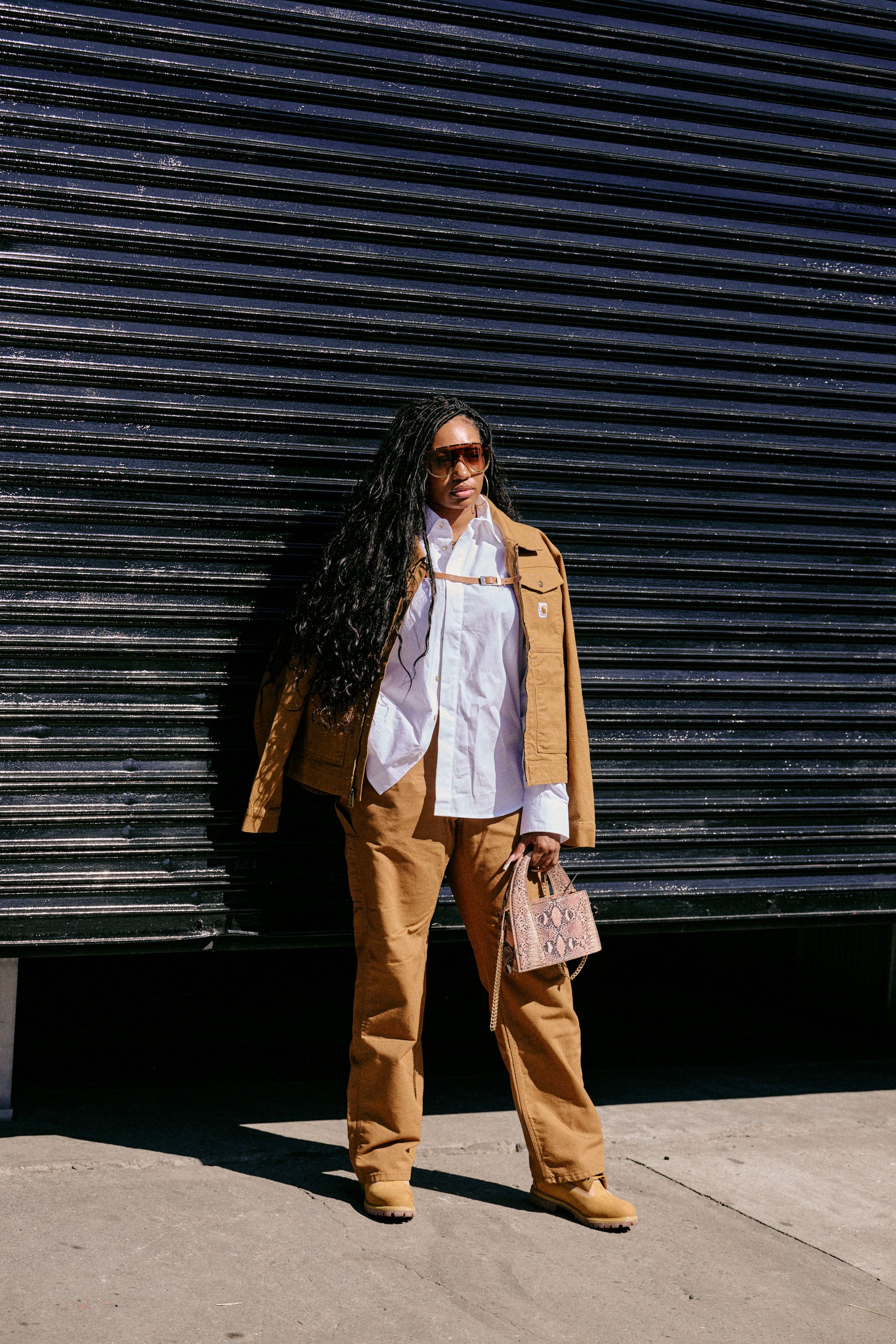 Man wearing a Carhartt barn jacket, white button down, cargo pants, and boots